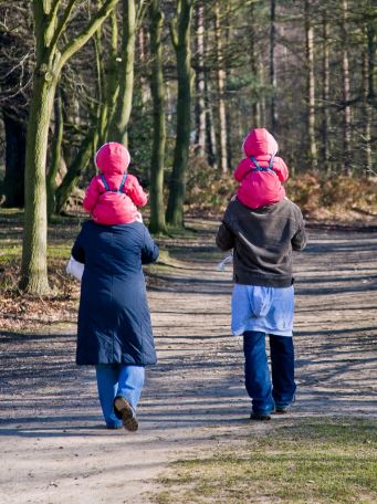 Fiatal pár nyakukban gyerekekkel tavaszi sétát tesz, Kép: pxhere