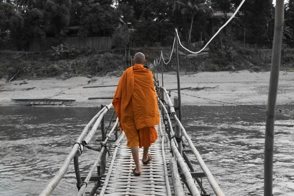 szerzetes sétál egy bambusz hídon Laoszban